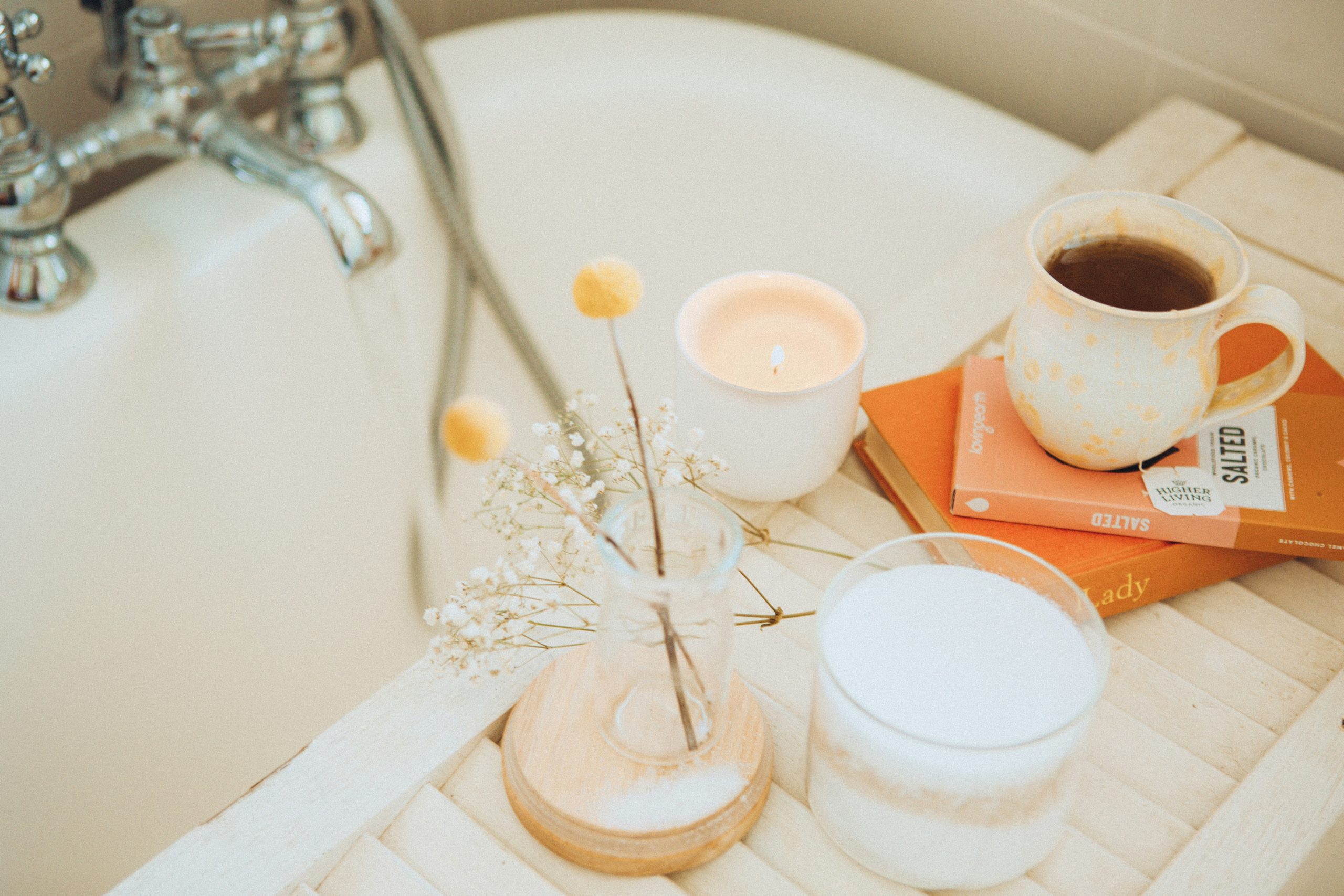 Coffee, book and candle by bathtub