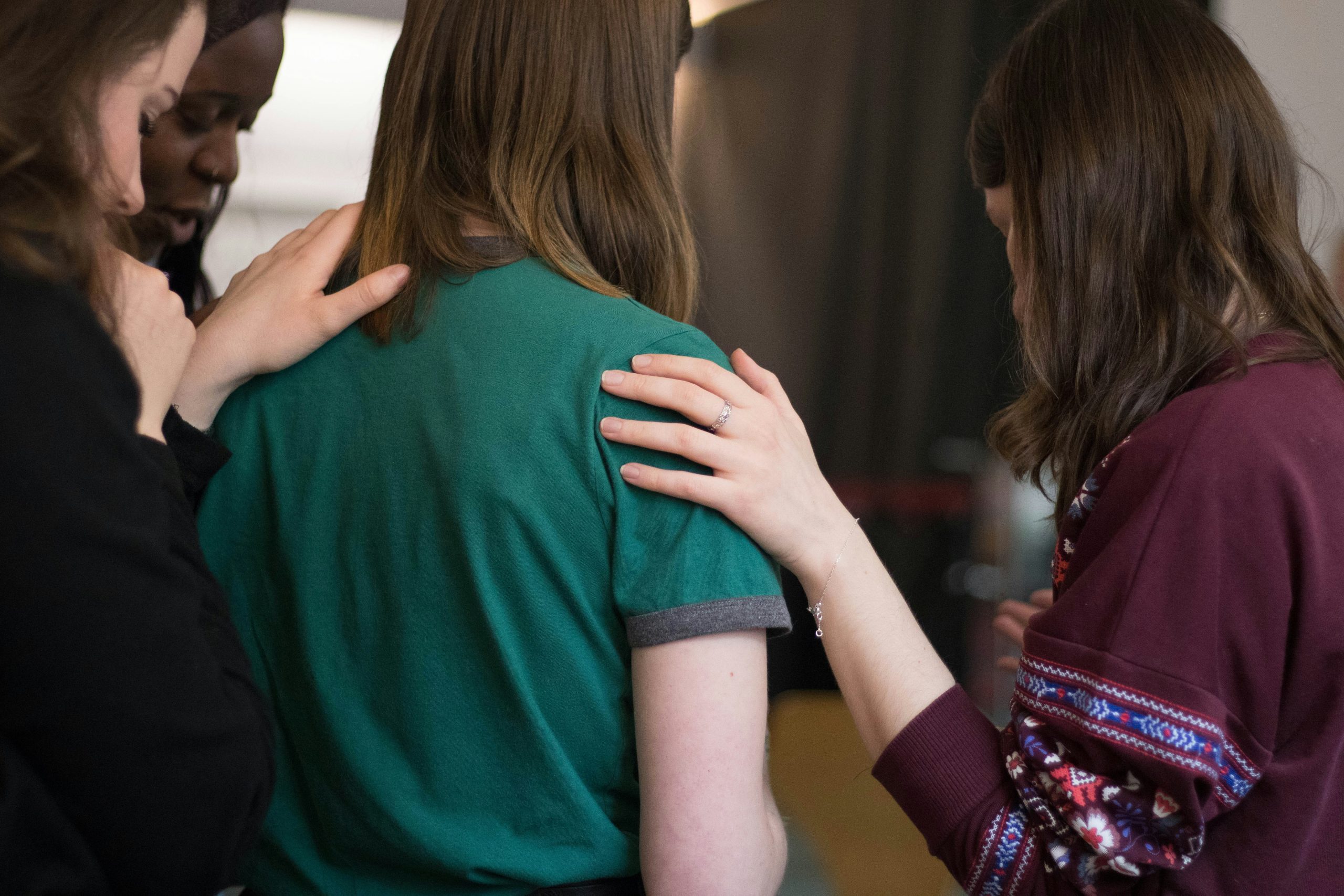 woman with other women's hands on her shoulders