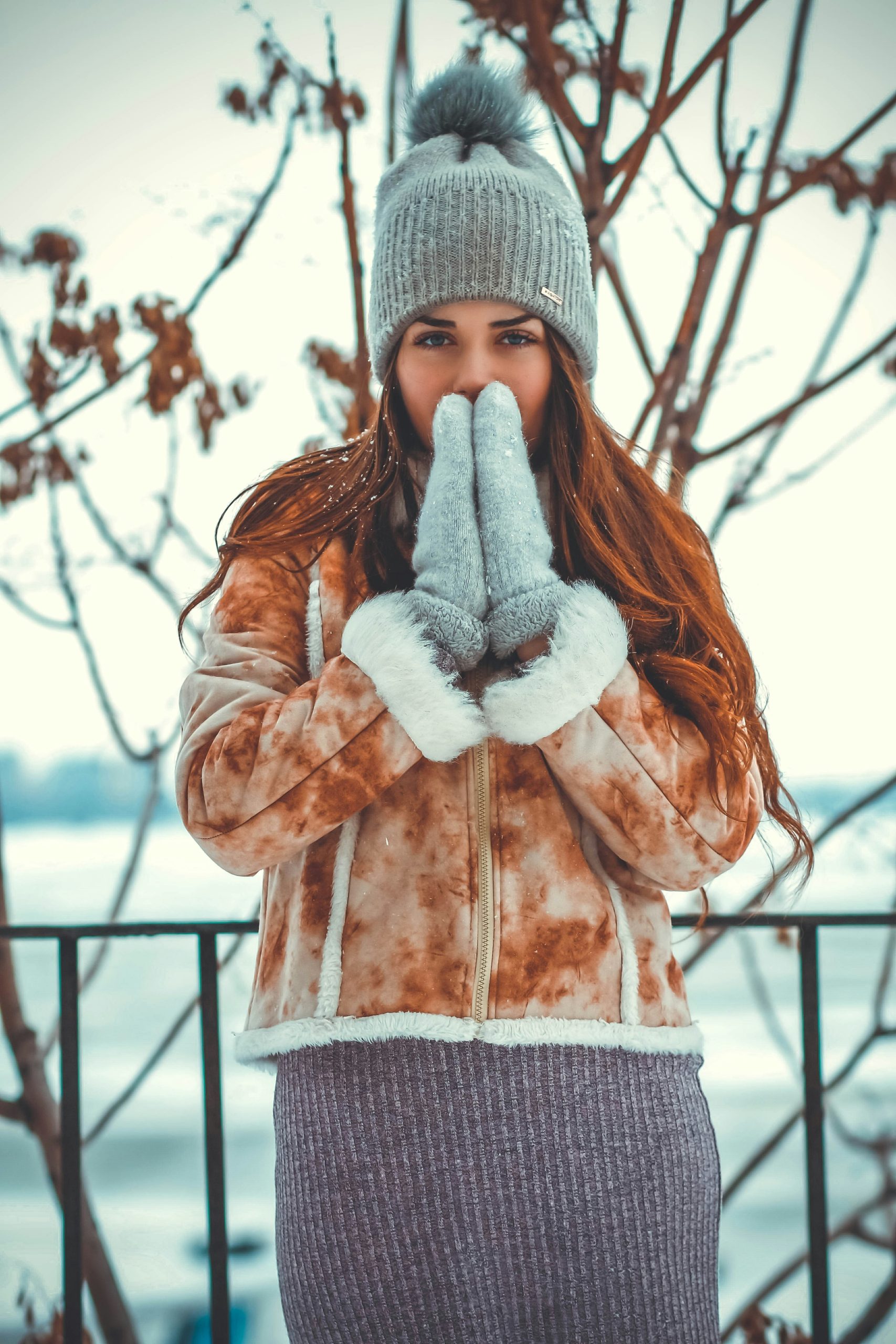 andrii-lievientsov-_1jIkgZ_Kl4-unsplash woman in winter coat and hat with mittened hands in front of her face